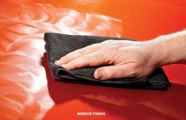 Close-up of hand polishing car panel with micro fibre cloth