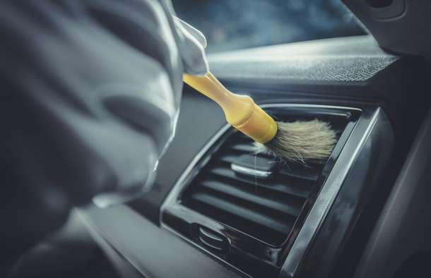 Close-up of cleaning a car air-vent with a detail brush