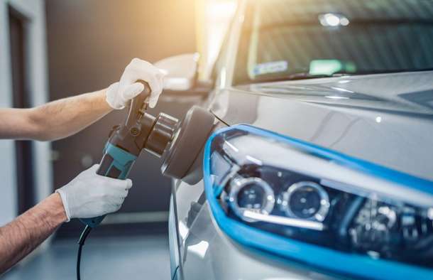 Close-up of an electric polisher buffing the side panel of a car