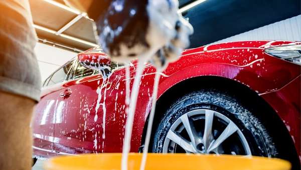 Squeezing soap suds into bucket while cleaning car