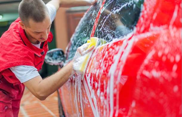 Washing the side of a car with a sponge and soap suds